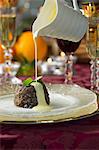 Custard being poured over Christmas pudding