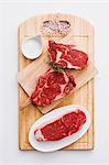 Various beef steaks and salt on a chopping board