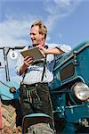 Mature man with digital tablet on tractor, Bavaria, Germany