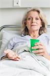 Patient in hospital holding cup and pills