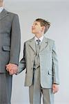 Father and son holding hands against white background