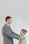 Father talking to son with hands on his shoulder, smiling