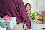 Senior man hand over present to woman on birthday, smiling