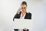 Portrait of businesswoman in black suit holding blank placard, smiling