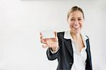 Portrait of businesswoman in black suit holding blank business card, smiling