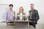 Businesspeople at speakers desk in auditorium, smiling
