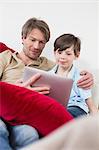 Father and son using digital tablet, smiling