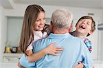 Grandfather hugging happy grandchildren