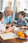 Children doing homework with their grandfather