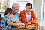 Grandfather, father and son playing backgammon