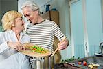 Mature couple preparing food, smiling