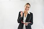 Portrait of businesswoman in black suit holding notebook and pen, smiling