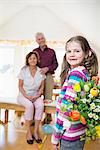 Granddaughter handover bouquet to her grandmother and grandfather in background