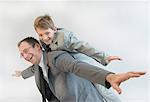 Father giving piggy back ride to his son, smiling