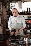 Cobbler in store holding pair of leather shoes