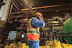 Engineer in electric power plant using his smartphone inside condenser room