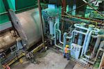 Engineer in gas turbine electric power plant exhaust gas and condensation process room reviewing meters