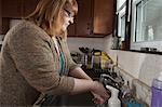 Woman who is legally blind washing dishes in her kitchen