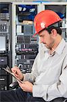 Network engineer with clip board reviewing control systems in data center