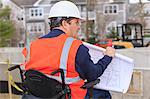 Construction engineer with spinal cord injury with house plans at construction site