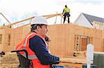 Construction engineer with spinal cord injury talking on radio at home construction site