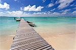 Wooden jetty with boats tied to it stretching out into the Indian Ocean off an idyllic beach on Ile Aux Cerfs, Mauritius, Indian Ocean, Africa