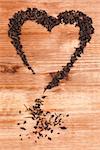 Organic dried green tea leaves in heart shape on wooden background. Traditional oriental beverage.