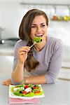 Happy young housewife eating greek salad