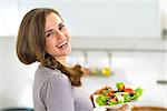 Portrait of happy young housewife with greek salad