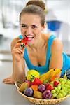 Closeup on young woman with fruits plate eating strawberry