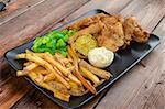 Fish and chips with homemade mayonnaise on black plate