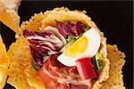 Parmigiano cheese basket filled with bacon and fresh vegetable. Culinary cheese eating.