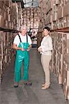 Warehouse worker and manager smiling at camera in a large warehouse