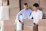 Pretty warehouse manager using laptop with colleague in a large warehouse