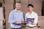 Pretty warehouse manager using tablet pc with colleague in a large warehouse