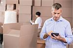 Warehouse manager using his calculator in a large warehouse