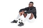 Full length of a serious football player sitting over white background