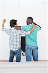 Rear view of two excited soccer fans watching tv