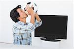 Side view of a football fan kissing ball against tv