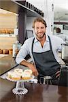 Handsome barista smiling at camera at the coffee shop