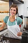 Pretty barista smiling at camera at the coffee shop