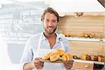 Handsome waiter holding tray of croissants at the coffee shop