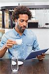 Handsome man using tablet while having coffee at the coffee shop