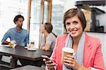 Pretty brunette sending a text drinking coffee at the coffee shop