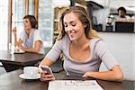 Pretty blonde sending text message at the coffee shop