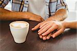 Couple enjoying a coffee holding hands at the coffee shop