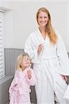 Mother and daughter brushing their teeth at home in the bathroom