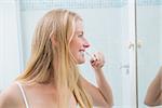 Happy woman brushing her teeth at home in the bathroom