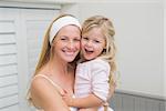 Happy mother and daughter hugging at home in the bathroom