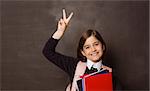 Cute pupil smiling at camera holding books on black background